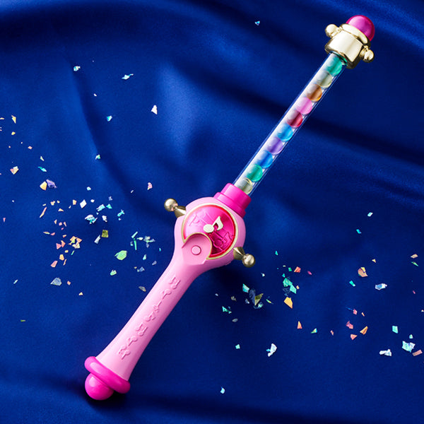 A colorful toy wand resembling the 'Pepertoporon' from the anime 'Ojamajo DoReMi', displayed on a blue background with sparkles around it.